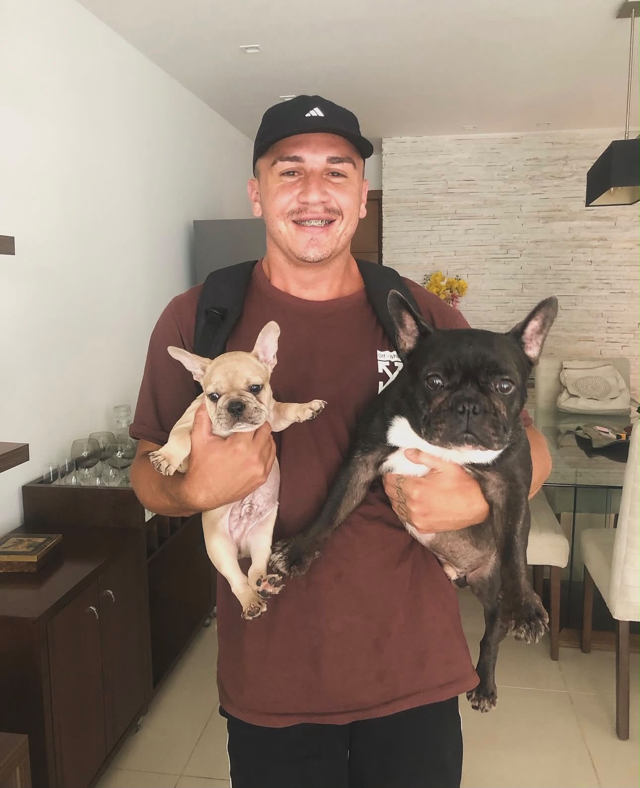 Biel com dois bulldogs franceses no colo dentro de casa